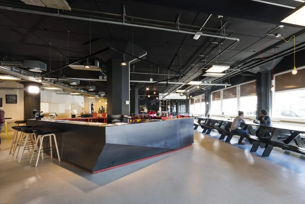 Moderne bedrijfsruimte aan de Anthony Fokkerweg met een centrale bar, industriële uitstraling en lange zitbanken bij de ramen.